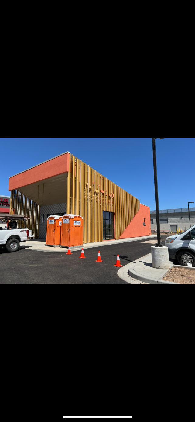 Commercial building exterior with a freshly painted coral façade and gold vertical metal fins