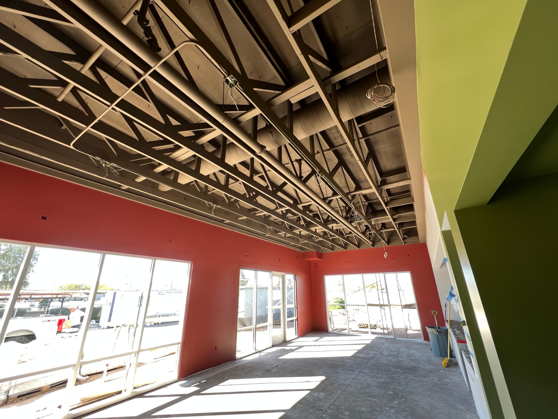 Interior space with a freshly painted red accent wall, green wall and painted exposed ceiling structure