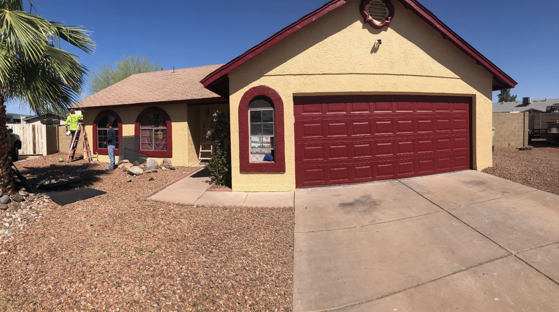 Phoenix area home exterior with yellow stucco walls, red trim and a red garage door during a professional repaint